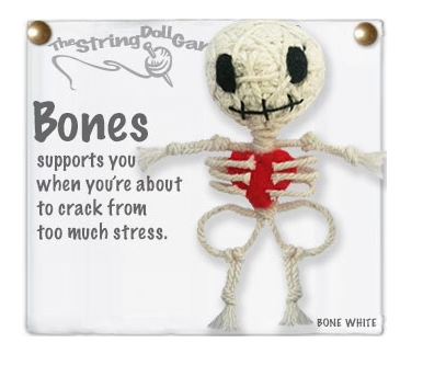 A keychain made out of string in the shape of skeleton. with two black eyes, a stitched mouth, and a red hear in the rib cage.