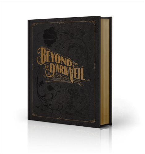 A black book with gold leaf pages and "Beyond the Dark Veil" written in gold serif font on the cover.