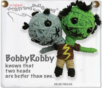 A keychain of a grey head and a green head, both with black hair and eyes, sharing one body. 