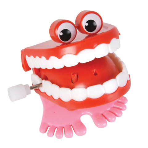 A wind-up toy of a red mouth with white teeth and pink feet, with two large eyes on top.