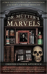 A bookshelf with various medical books, tools, and tincture bottles. There is a framed photo of Dr. Mütter and a skull, all between two columns.