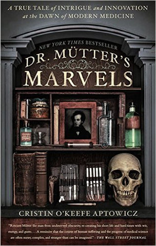 A bookshelf with various medical books, tools, and tincture bottles. There is a framed photo of Dr. Mütter and a skull, all between two columns.