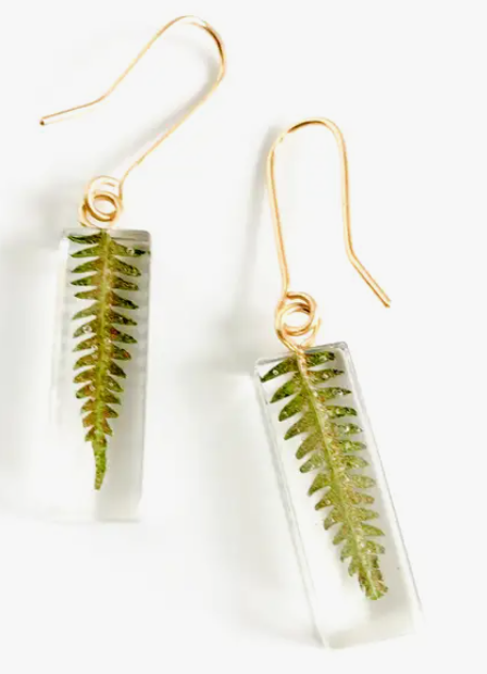 Two earrings with long gold ear hooks. Each earring has a rectangle made of resin with a piece of green fern inside it.