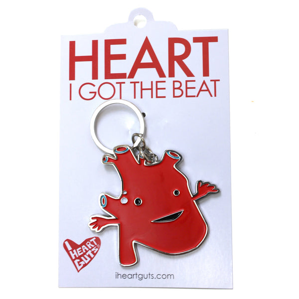 A white card with "Heart I Got the Beat" written on it with red letters. There is a red enamel keychain in the shape of an anatomical heart with a smile and two eyes.