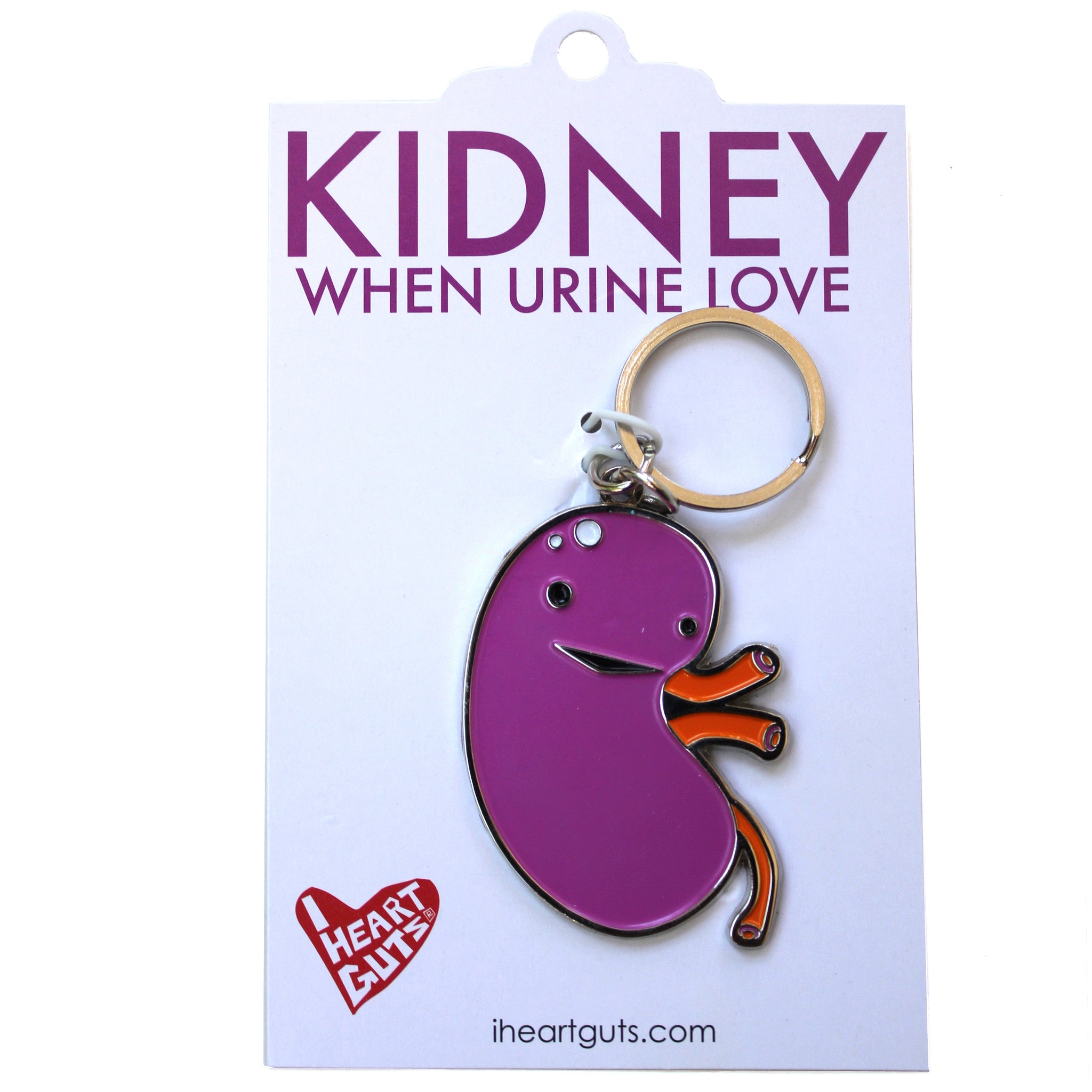 A white card with "Kidney When Urine Love" written on it in purple letters. There is a purple and orange enamel keychain in the shape of a kidney with a smile and two eyes on it.