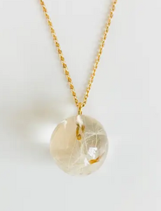 A gold chain with a resin sphere containing dandelion seeds and puffs inside it.