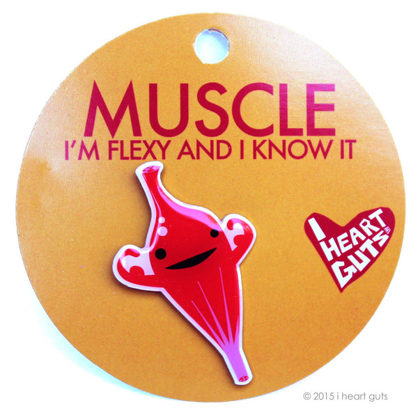 An orange card with "Muscle I'm Flexy and I Know it" written on it in red letters. There is a red enamel pin of an illustration of a muscle flexing its arms with two eyes and a smile.