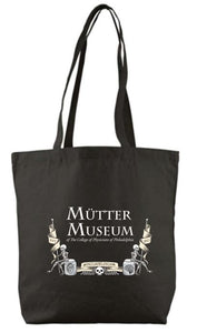 A black tote bag with the Mütter Museum logo imprinted in white. There are two skeletons on either side, sitting on a jar with a hear and a jar with a brain. Each skeleton holds a flag with "est. 1863" on it and there is a skull in between them below a banner with "Philadelphia" written in it.