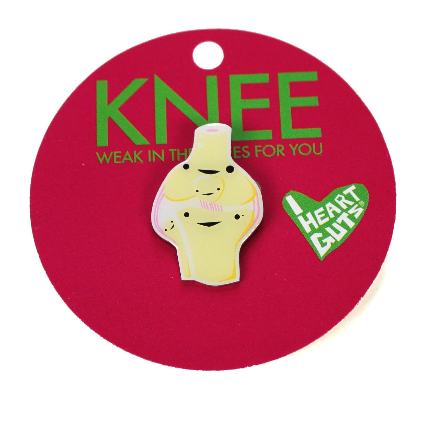 A red card with "Knee Weak in the Knees for You" written on it in green letters. There is a cream enamel pin in the shape of a knee with faces on the different sections.